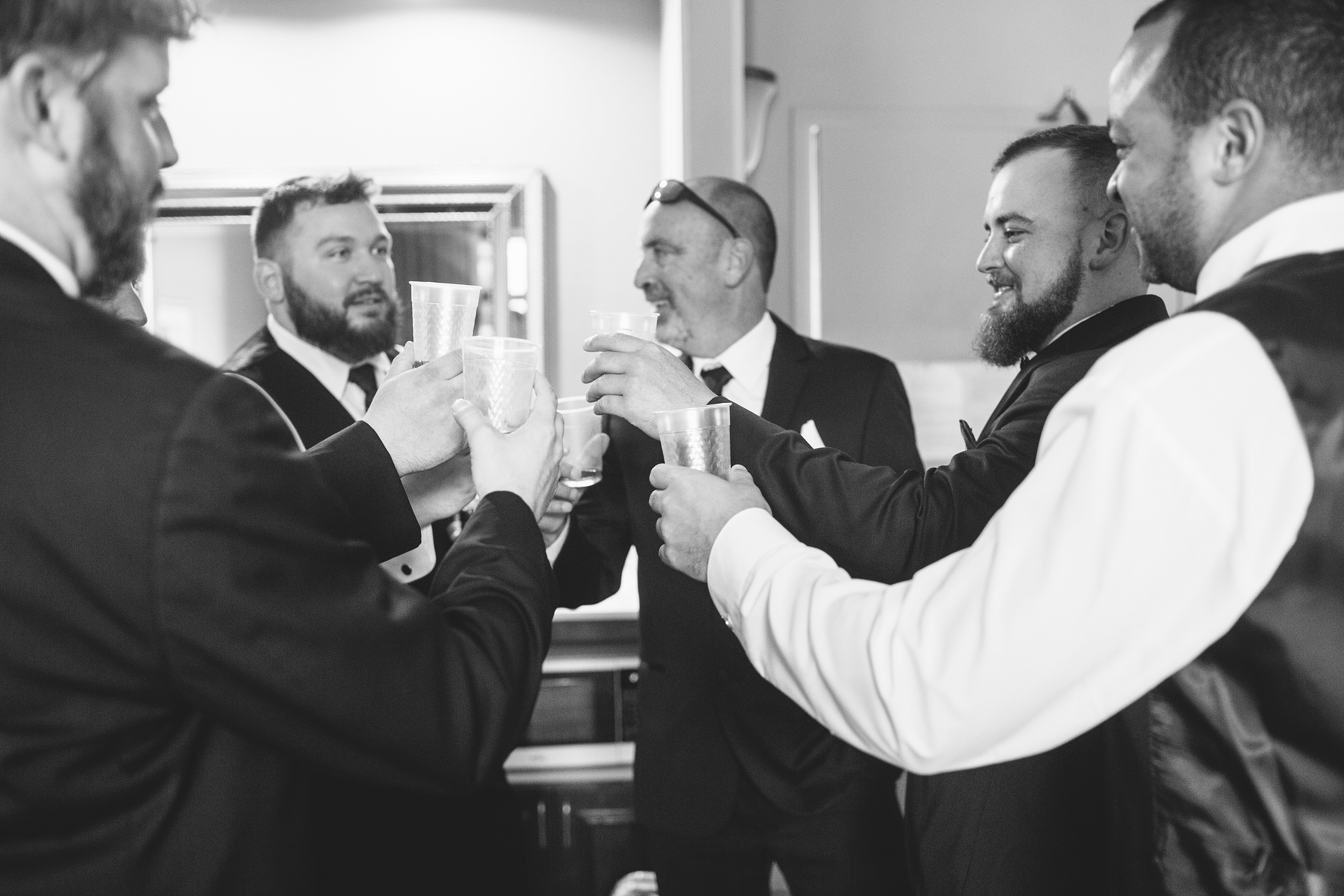 Groom and guys on wedding day with drinks.