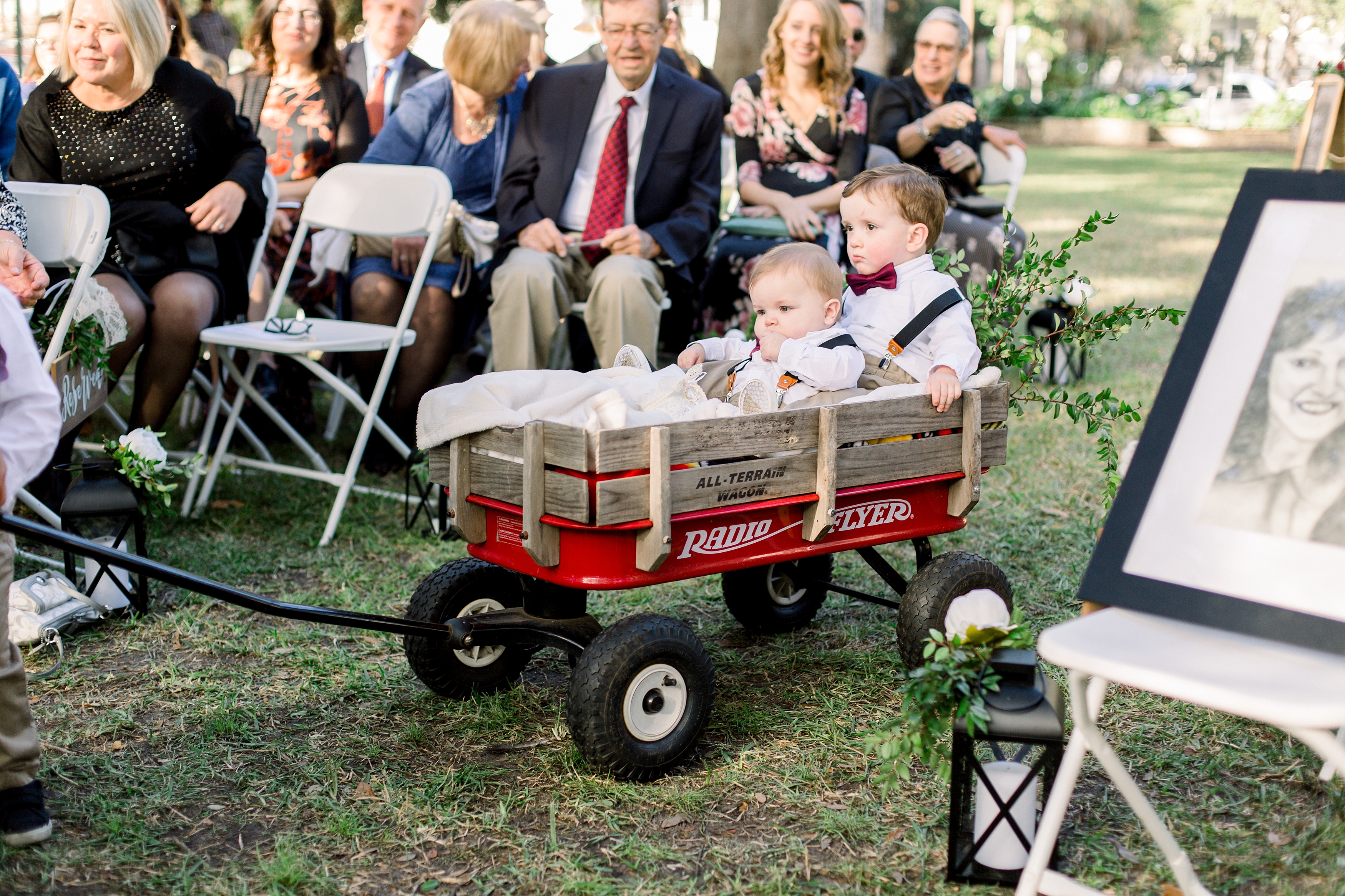 Little boy ring bearers in wagon coming down aisle.