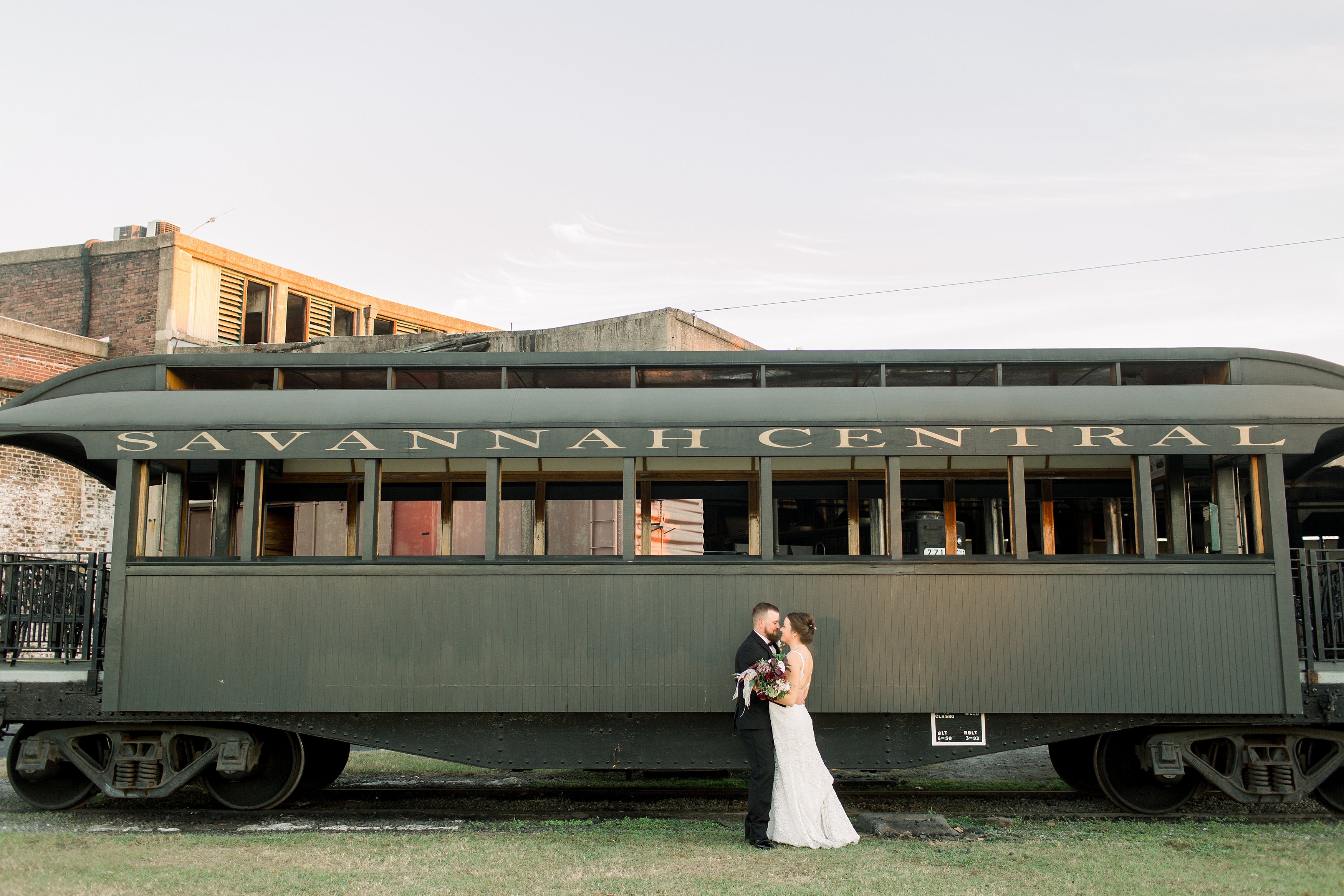 Bride and groom in front of train car at Georgia State Railroad Museum.