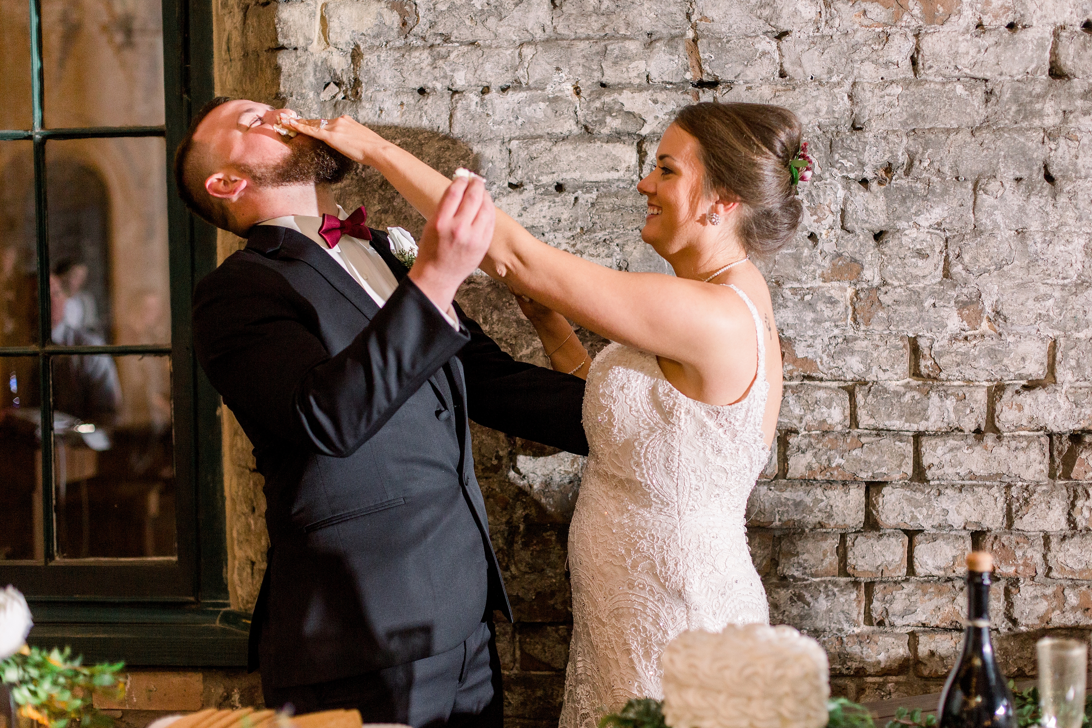 Bride and groom smashing cake in each other's faces. 