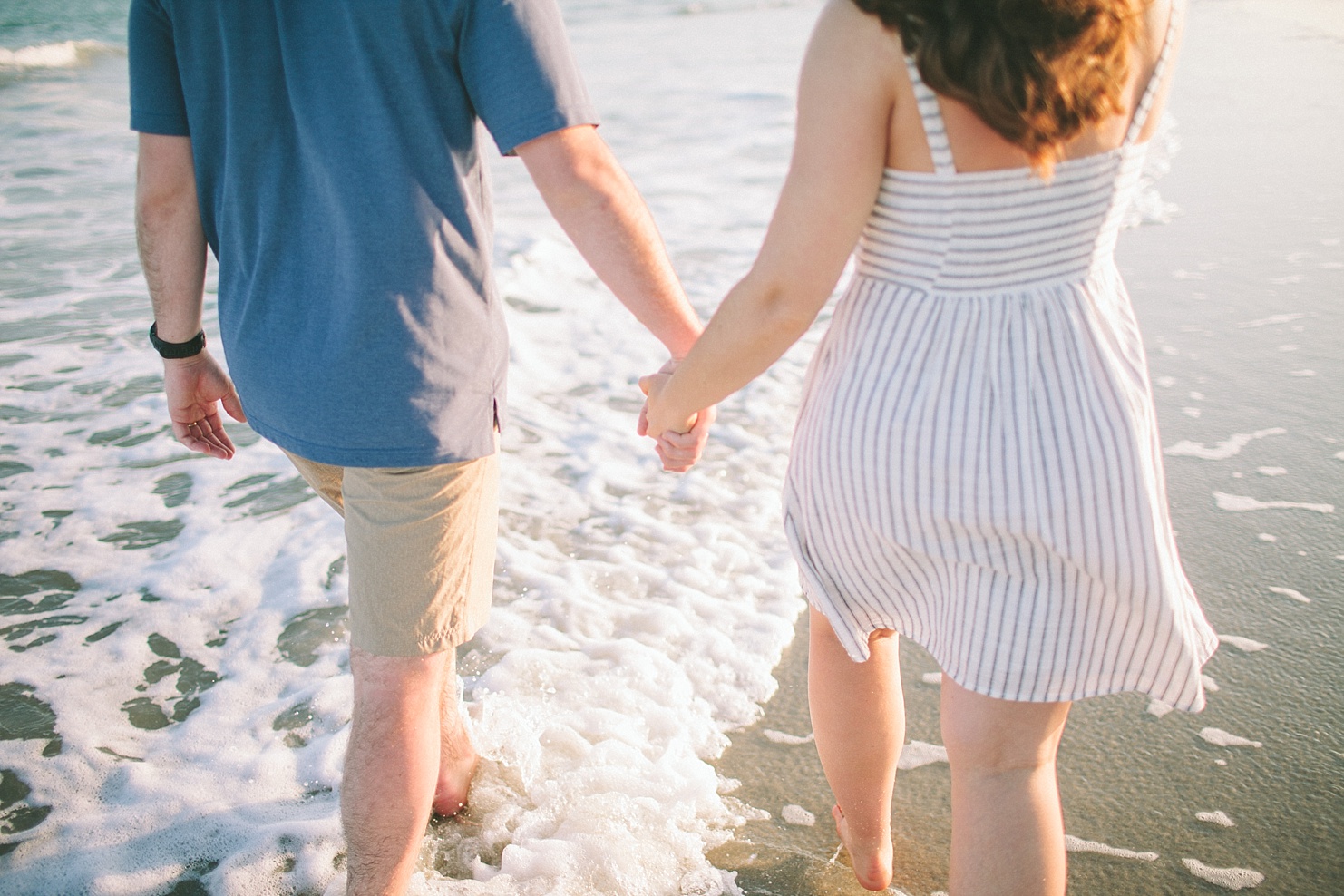Couple holding hands walking in the water